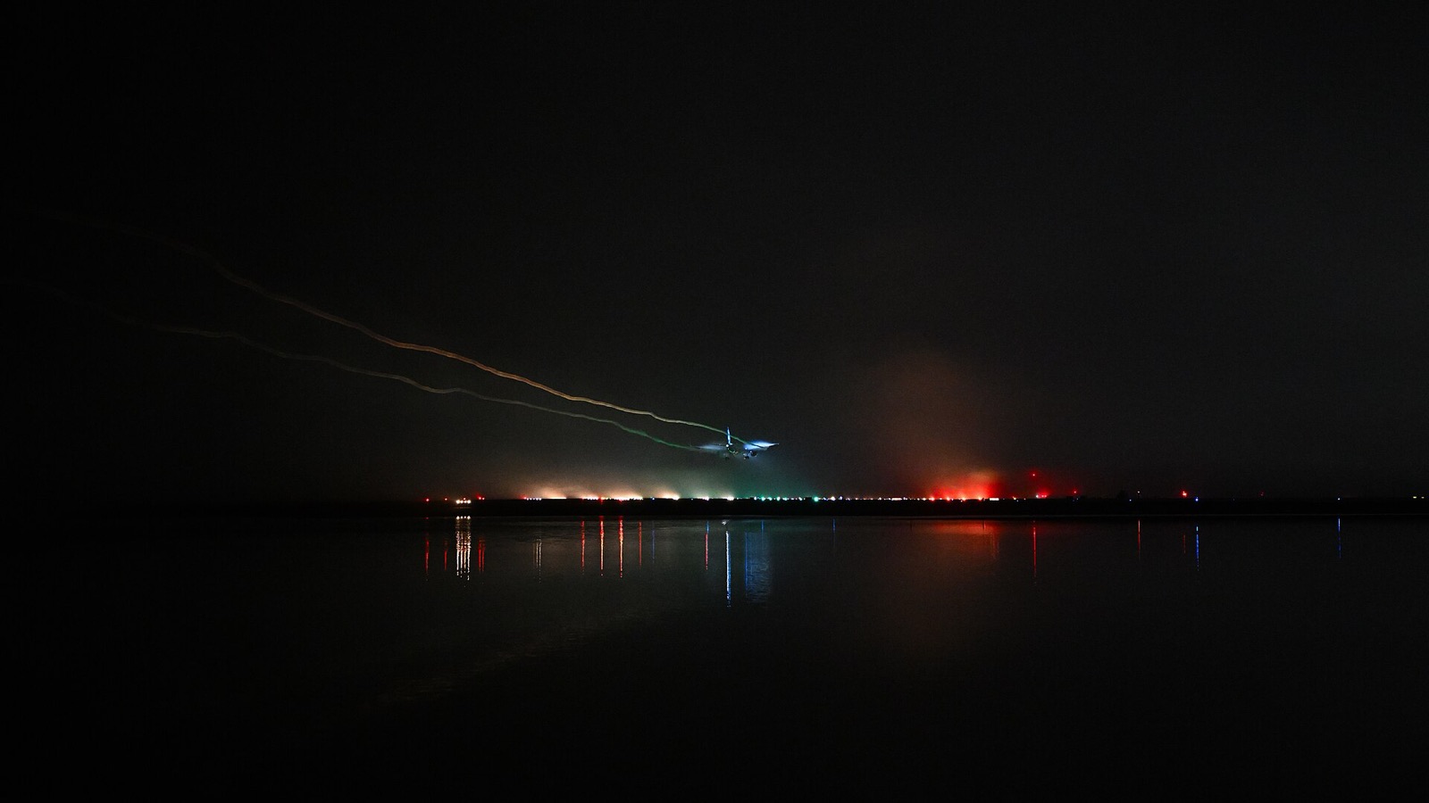 An airliner landing at night in fog over the approach lights